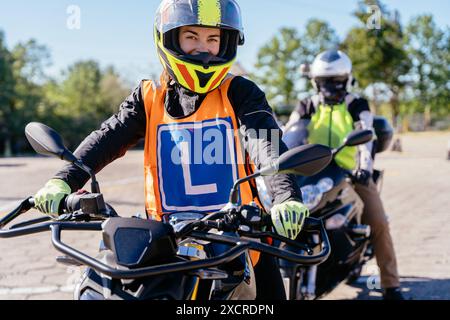 Eine Frau mit gelbem Helm und orangefarbener Weste fährt Motorrad Stockfoto