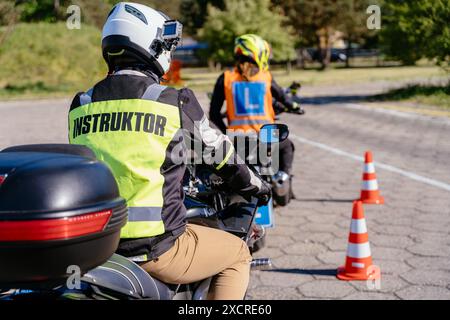 Ein Mann in einer gelben Jacke mit dem Wort Instruktor sitzt auf einem Motorrad Stockfoto