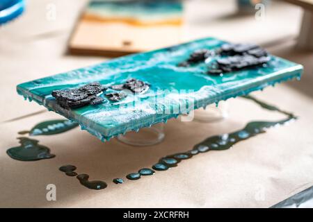 Beeindruckendes Epoxidharz-Meisterwerk trocknet. Überschüssige blaue azurblaue Flüssigkeit gefriert auf der Tischwerkbank Stockfoto