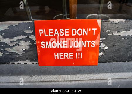 Ein Schild auf einer Bank vor einem Cannabis rauchenden Café in Amsterdam, Niederlande, steht: "Bitte rauchen Sie hier keine Joints" Stockfoto