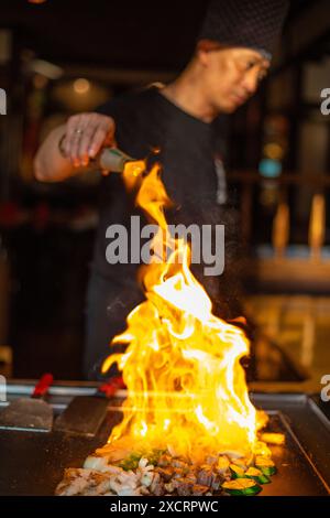 Berlin, Deutschland 08. 16. 2023. Der Teppanyaki-Koch kocht im Teppan in einem japanischen Steakhaus. Der japanische Koch zeigt eine Show mit Feuer und Flammen Stockfoto