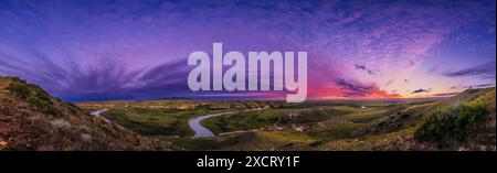 Ein Panorama der Landschaft und des Himmels bei Sonnenuntergang im Writing-on-Stone Provincial Park (Áísínai'pi) in Alberta, mit dem sich der Milk River unter den Wellen windet Stockfoto