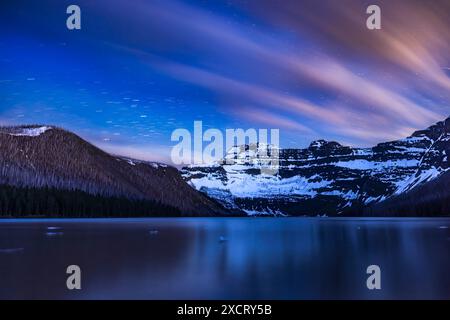 Die Sterne und Wolken ziehen sich über den Cameron Lake im Waterton Lakes National Park, Alberta und Mt. Custer auf der anderen Seite der Grenze im Gletscher Nati Stockfoto