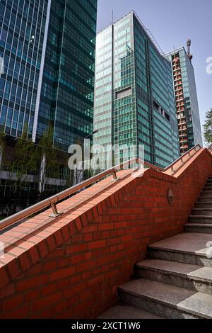 Treppen neben der roten Backsteinmauer und Fassaden moderner Bürogebäude in Posen, Polen Stockfoto