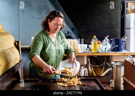 Die historische Schlägerin und Schiffseignerin Anne kocht in einer alten Werftküche ein Surina-Gericht/Wrap für ihre Bewohner aus der Nachbarschaft. Rotterdam, Niederlande. Stockfoto