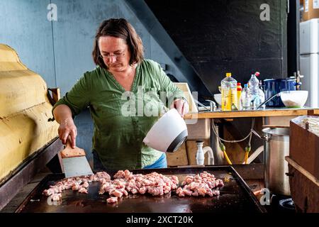 Die historische Schlägerin und Schiffseignerin Anne kocht in einer alten Werftküche ein Surina-Gericht/Wrap für ihre Bewohner aus der Nachbarschaft. Rotterdam, Niederlande. Stockfoto