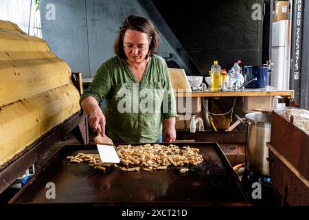 Die historische Schlägerin und Schiffseignerin Anne kocht in einer alten Werftküche ein Surina-Gericht/Wrap für ihre Bewohner aus der Nachbarschaft. Rotterdam, Niederlande. Stockfoto