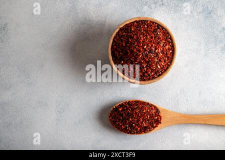 Pfefferflocken, rote Chili-Paprika in Holzschale auf hellblauem Hintergrund Stockfoto