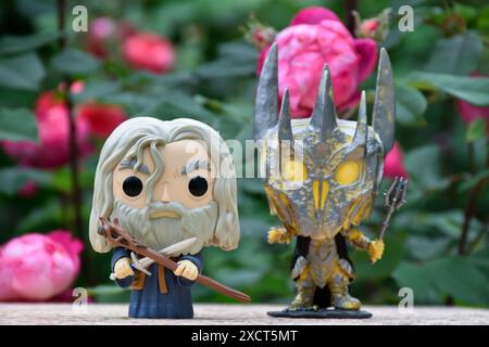 Funko Pop Actionfiguren des Zauberers Gandalf der graue und des dunklen Lord Sauron aus dem Fantasy-Film der Herr der Ringe. Geheimnisvoller, stimmungsvoller Garten, rote Rosen. Stockfoto