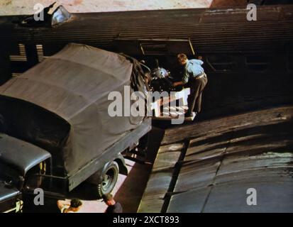 Ein Foto zeigt Arbeiter, die während des Zweiten Weltkriegs einen Motor in ein Junkers Ju 52-Flugzeug laden. Dieses vielseitige und zuverlässige Flugzeug war entscheidend für die Lieferung von kritischen Vorräten, einschließlich Motoren, an Frontpositionen. Die Fähigkeit der Ju 52, schwere und wichtige Ausrüstungen zu transportieren, sorgte dafür, dass die deutschen Truppen an verschiedenen Schlachtfronten einsatzbereit blieben. Stockfoto