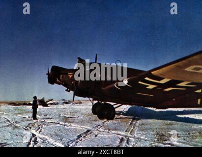 Ein Foto zeigt ein Flugzeug der Junkers Ju 52, das während des Zweiten Weltkriegs auf einem schneebedeckten Flugplatz landete. Der Betrieb unter rauen Winterbedingungen erforderte qualifizierte Piloten und robuste Flugzeugwartung. Die Ju 52 war ein vielseitiges und zuverlässiges Arbeitspferd für die Luftwaffe, das für den Transport von Truppen, Vorräten und Ausrüstung eingesetzt wurde, besonders wichtig bei Winterkampagnen, als der Bodentransport oft durch Schnee und Eis behindert wurde. Stockfoto