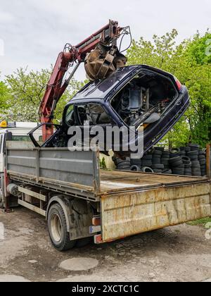 Verladung eines verlassenen Wracks mit einem hydraulischen Ladekran auf einer Abschleppwagenplattform, Verwertung des Fahrzeugs Stockfoto