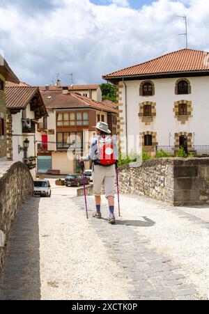 Pilgerfrau, die die Brücke in das spanische Dorf Zubiri überquert hat, nachdem sie den Jakobsweg von Roncesvalles Spanien aus durchlaufen hat Stockfoto