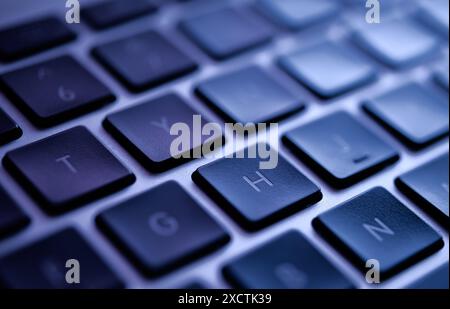 Nahaufnahme einer modernen, blau beleuchteten Laptop-Tastatur, die potenzielle Datenschutzverletzungen, Cybersicherheitsbedrohungen und Schwachstellen hervorhebt. Stockfoto