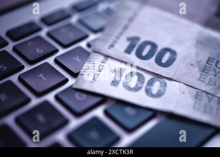 Ein Nahfoto, das eine 100-Euro-Banknote auf einer Laptop-Tastatur zeigt, die elektronische Finanzen und Online-Transaktionen sowie Cyberkriminalität betont Stockfoto