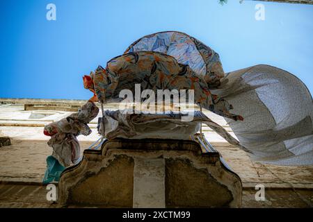 Charmanter süditalienischer Balkon mit wehenden Laken, die vom Balkon hängen, schwanken sanft im Wind und schaffen wunderschöne, fließende Kurven Stockfoto