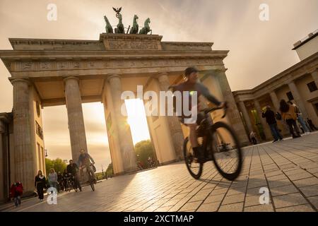 Berlin, Deutschland – 4. MAI 2023: Touristen und Radfahrer besuchen das Brandenburger Tor bei Sonnenuntergang, während die Sonne dahinter auf dem Pariser Platz in Berl untergeht Stockfoto