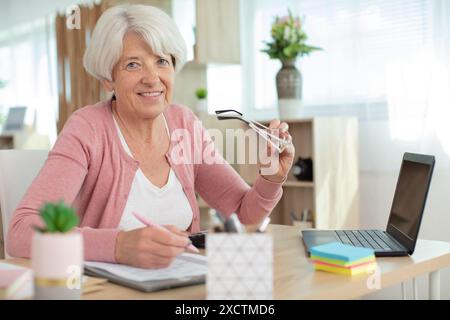 Glückliche Seniorin zieht Papierkram in Betracht Stockfoto