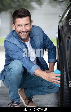 Mann Arbeiter, der Autos Alufelgen auf einer Autowaschanlage wäscht Stockfoto