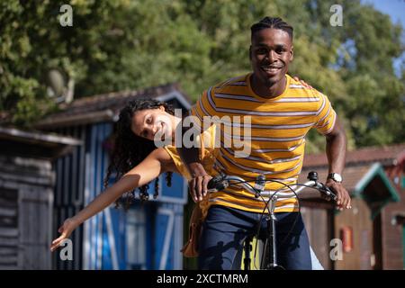 Multirassisches junges Paar, das auf einem Fahrrad fährt und Spaß hat Stockfoto