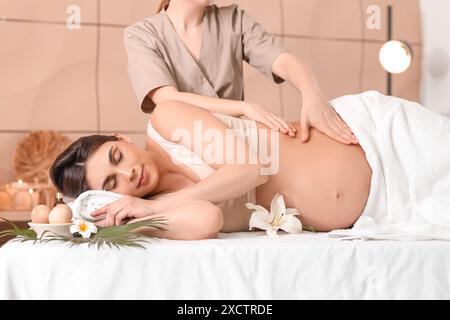 Junge schwangere Frau mit Massage im Spa-Salon Stockfoto