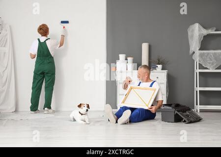 Ein paar ältere Dekorateure mit Hund, der im Zimmer repariert Stockfoto