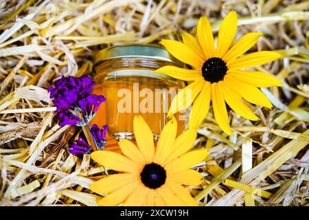 Glas Honig in Strohhalm mit Lavendel- und Rudbeckia-Blüten Stockfoto