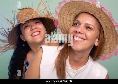 Porträt zweier lächelnder junger, schöner Frauen mit traditionellem Strohhut vom Festival von Sao Joao. Isoliert auf hellgrünem Hintergrund. Stockfoto