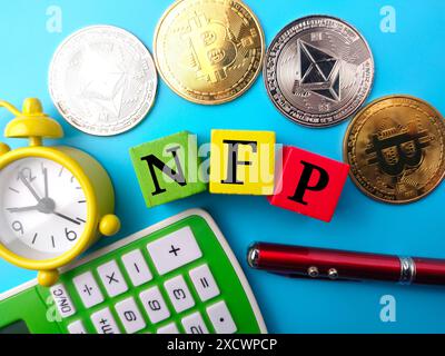 Uhr, Stift, Taschenrechner, goldener Bitcoin, silberner ethereum und farbiger Würfel mit Text NFP auf blauem Hintergrund. Stockfoto