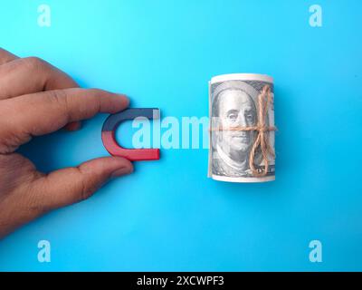 Handmagnet mit Draufsicht für Geldanziehungen auf blauem Hintergrund. Stockfoto