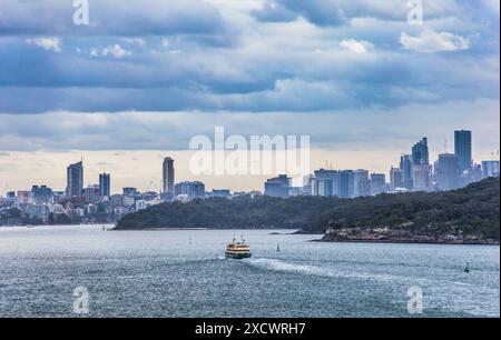 Eine Fähre, die durch den North Harbour in Richtung Middle Head mit der Skyline von Sydney dahinter fährt, Sydney Harbour, New South Wales, Australien Stockfoto