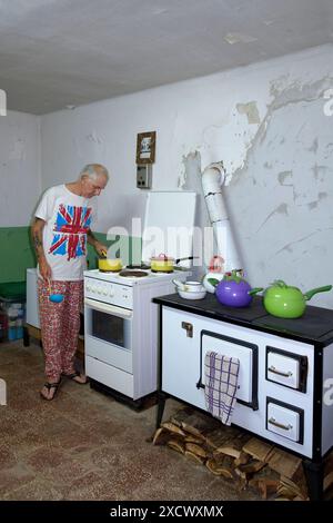 Reife männliche britische Expat in angemessener Kleidung kochen Essen in seiner Küche für andere Expats zala County ungarn Stockfoto