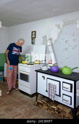 Reife männliche britische Expat in angemessener Kleidung kochen Essen in seiner Küche für andere Expats zala County ungarn Stockfoto