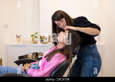 Kosmetikerin, die Wimpernlaminierung und Färbeverfahren macht. Junge lateinfrau in einer professionellen Schönheitssalon-Behandlung. Stockfoto