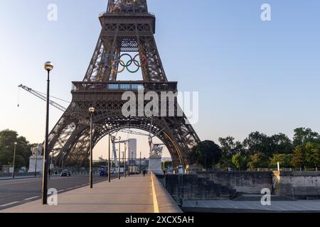 Paris, Frankreich - 07. Juni 2024: Eiffelturm im frühen Morgenlicht. Logo der Olympischen Spiele auf dem Turm und Baukran auf dem Boden. Sichtbare Personen Stockfoto