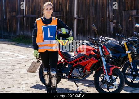 Frau in orangefarbener Weste mit mir neben rotem Motorrad Stockfoto
