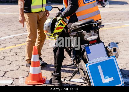 Ein Mann in einer gelben Weste steht neben einem Motorrad mit einem gelben Helm drauf Stockfoto