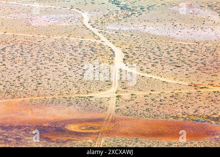 Eine gewundene, unbefestigte Straße führt durch eine karge Wüste. Luftaufnahme der Namib-Wüste in Namibia, Afrika Stockfoto