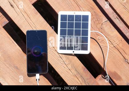 Laden eines Mobiltelefons im Freien mit einem Solarladegerät Stockfoto