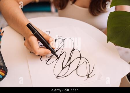 Lady zeichnet mit einem schwarzen Filzstift auf einem weißen Blatt Stockfoto