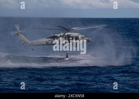 PHILIPPINE SEA (15. Juni 2024) U.S. Navy Lt. Cmdr. Virginia Nava, die der Carrier Strike Group (CSG) Nine zugeordnet ist, springt von einem MH-60S Meer in den Ozean Stockfoto