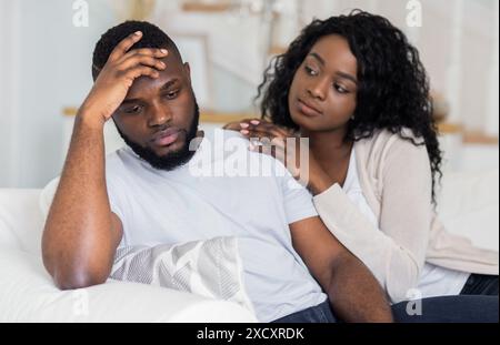 Frau tröstet aufgebrachten Mann auf der Couch Stockfoto