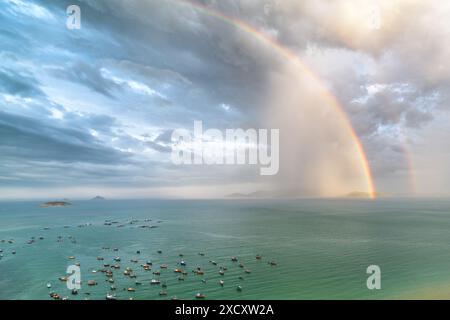 Fantastischer doppelter Regenbogen über der Nha Trang Bucht des Südchinesischen Meeres. Fantastischer Blick aus der Vogelperspektive auf traditionelle vietnamesische Fischerboote in der Bucht. Stockfoto