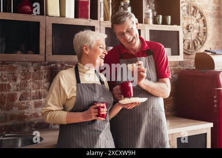 Seniorenpaar genießt Kaffee und Kekse in ihrer Küche Stockfoto