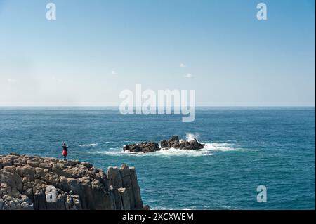 Ein Tourist genießt den spektakulären Blick auf das Japanische Meer von den Basaltklippen von Tojinbo in der Präfektur Fukui in Japan. Stockfoto