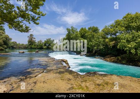 Das wunderschöne blaue Wasser des Manavgat Wasserfalls in der Nähe der türkischen Stadt Side in der Nähe von Antalya in der Türkei an einem sonnigen Tag mit heller Sonne und Bäumen. Stockfoto