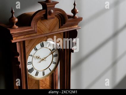 Eine antike, an der Wand montierte Großvateruhr aus Holz mit römischen Ziffern und einer Glastür auf einem schwach beleuchteten Innenhintergrund - 3D-Rendering Stockfoto