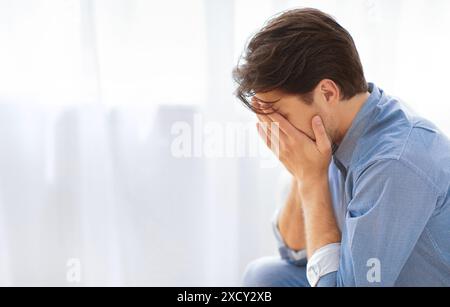 Mann, der das Gesicht mit Händen bedeckt, in Traurigkeit Stockfoto