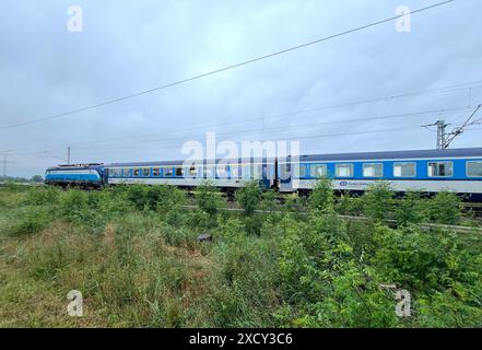 19. Juni 2024, Brandenburg, Prösen: Die Eurocity auf dem Weg nach Prag wurde auf dem offenen Gleis gestrandet, nachdem ein Baum auf die Freileitung fiel. Die Fahrgäste mussten den Zug verlassen und wurden mit dem Bus weiter befördert. Ein Gewitter verursachte am Dienstagabend an einigen Stellen beträchtliche Schäden. Foto: Andreas Richter/dpa Stockfoto