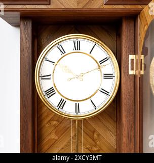 Eine antike, an der Wand montierte Großvateruhr aus Holz mit römischen Ziffern und einer Glastür auf weißem Hintergrund - 3D-Rendering Stockfoto